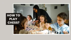 Children learning how to play chess for beginners with help from their teacher in a classroom