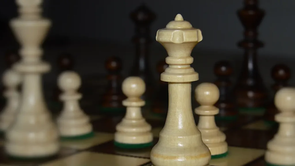 Close-up of wooden chess pieces on a board, queen and pawns in focus